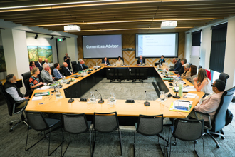 Committee members around a meeting table in a council chamber