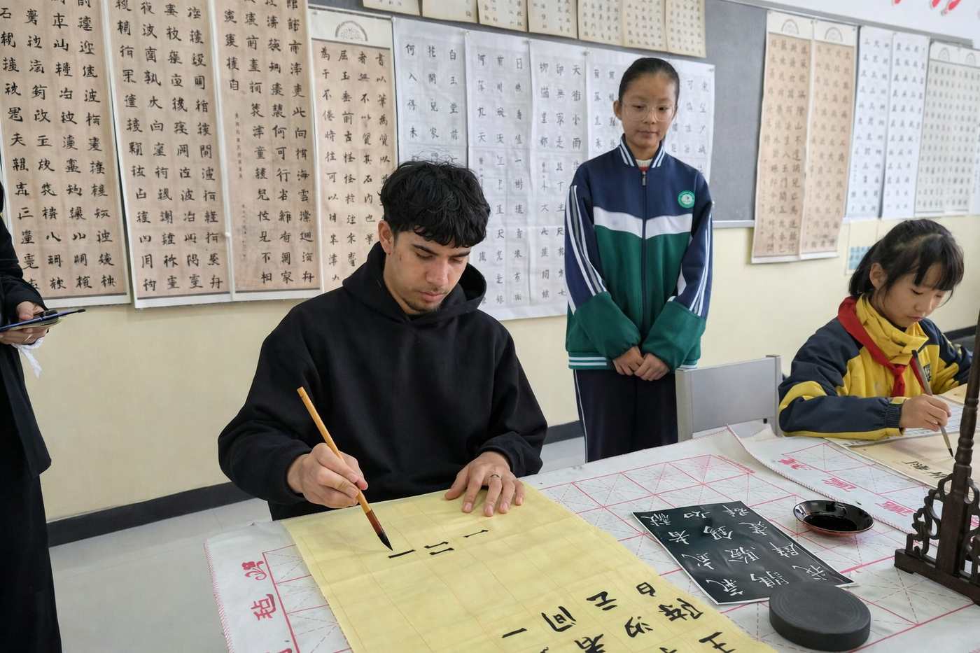 Volunteer Tamati practising Chinese calligraphy alongside students