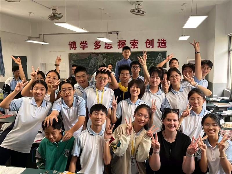 志愿者与合作学校师生合影 / A volunteer with host-school students in their classroom